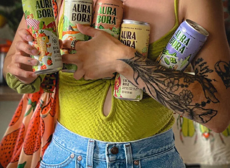 Woman balancing five different Aura Bora sparkling water flavors