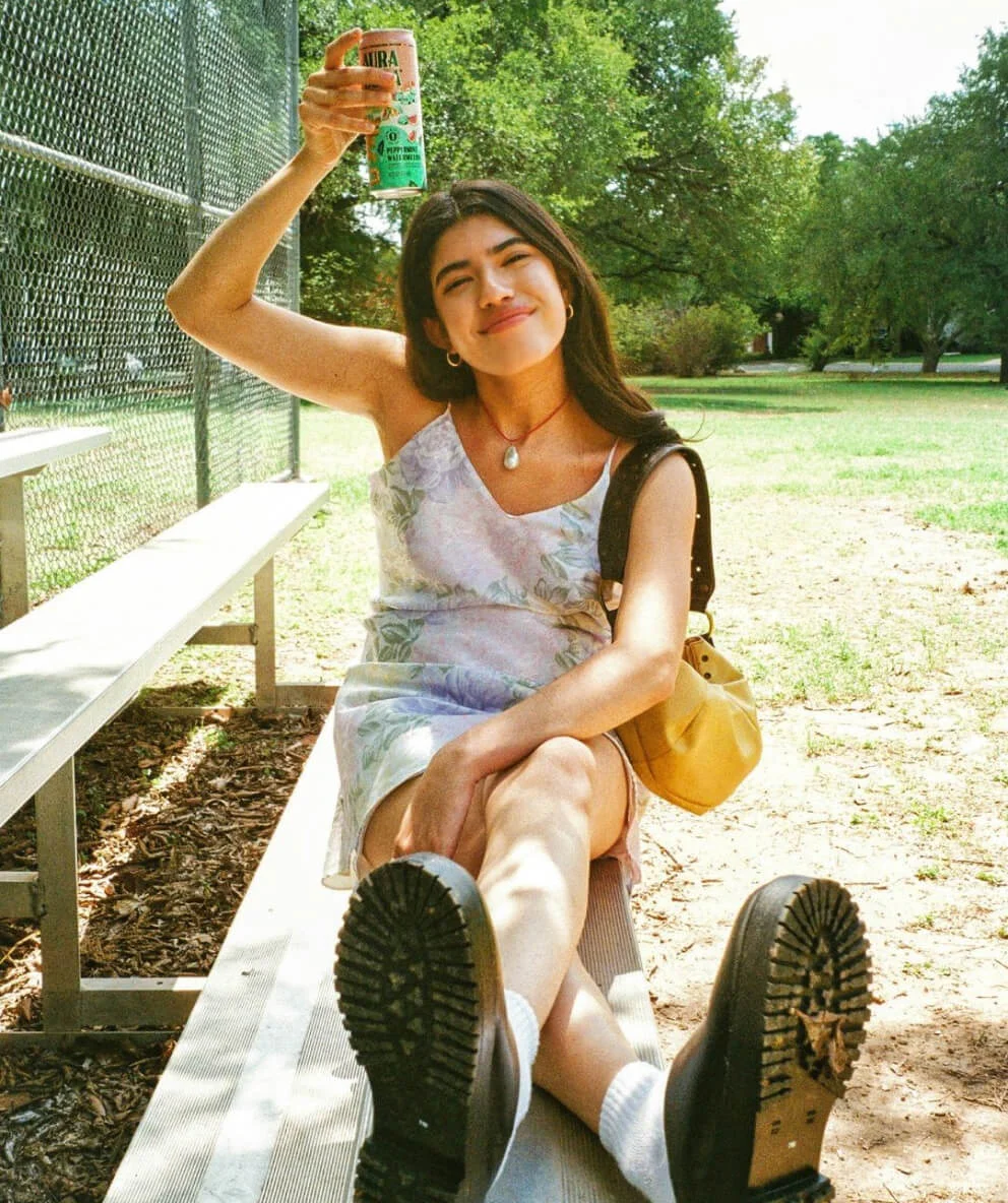 Woman drinking peppermint watermelon Aura Bora sparkling water in a park